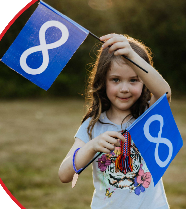 Young girl smiling outdoors while holding two blue Métis flags