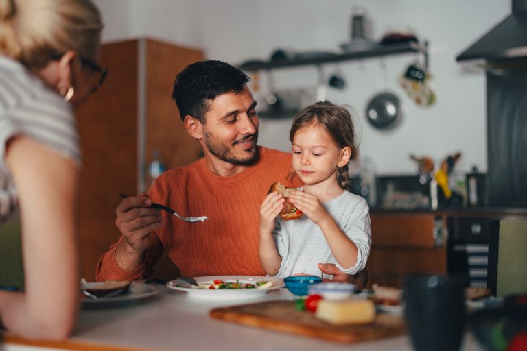 Young girl eating breakfast at the kitchen table with her family